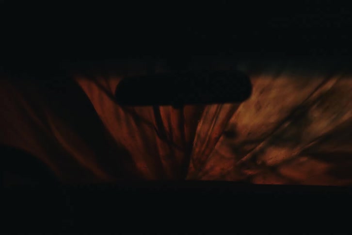 Interior view of the car with lights reflected on the windshield and a cover being removed by a woman
