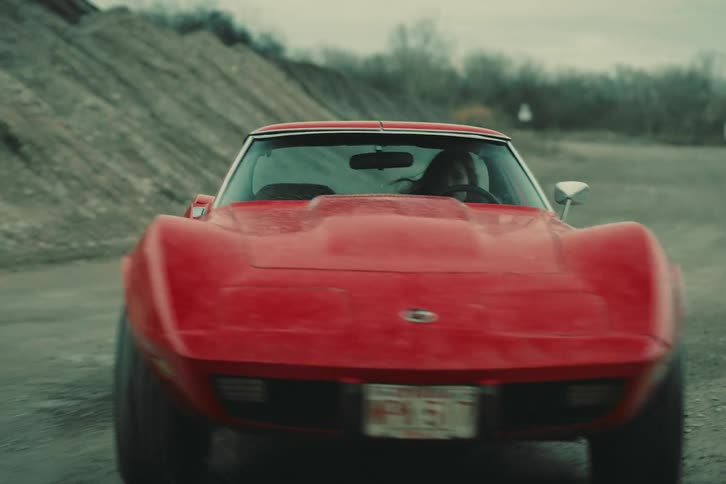 A young woman drives a red stingray in a gravel quarry on a winter day