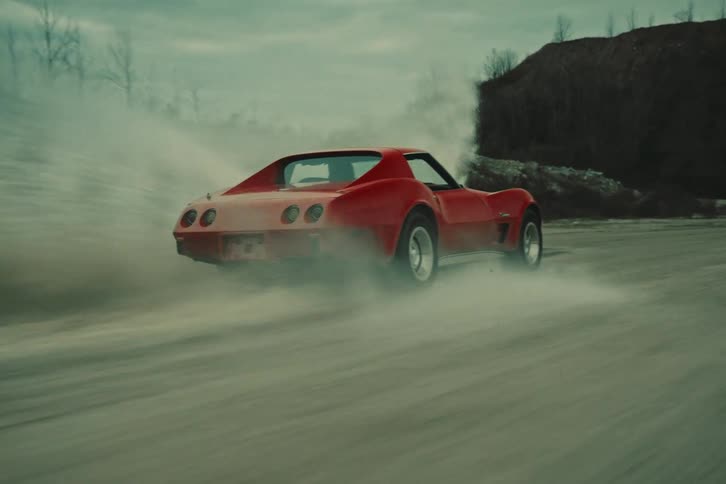A red car driving at high speed on a dirt road
