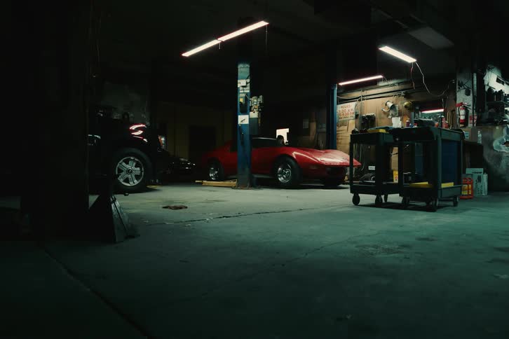 A red car in a garage drives a little and stops