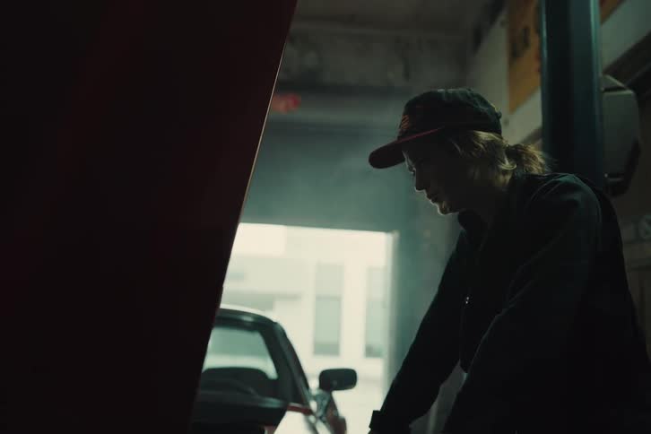 A woman mechanic is looking at fixing something in an engine of a car with an open hood