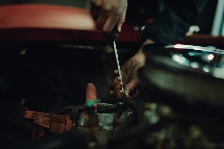 Hands of a mechanic tightening screws on a car engine