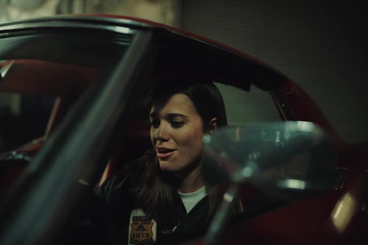 A happy woman starting a car engine in the garage