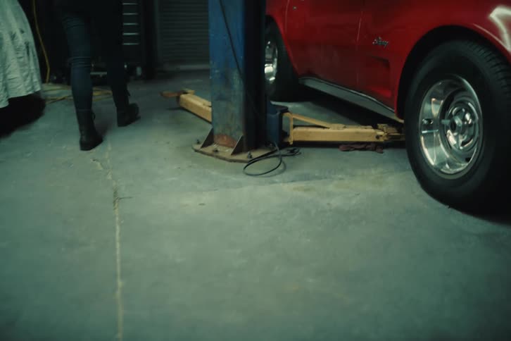Woman observing a red sports car in a garage
