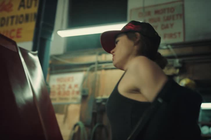 Mechanic woman emerging from under the car and then removing coveralls