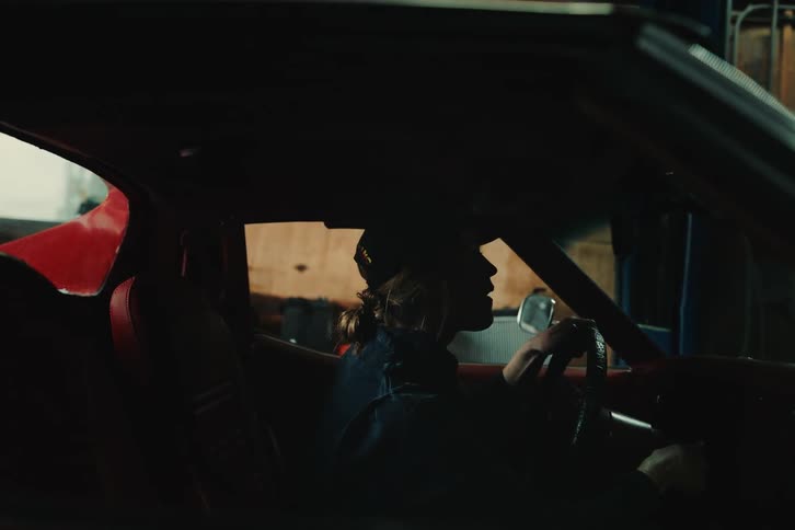 A woman struggles to start up a vehicle that is parked in a garage