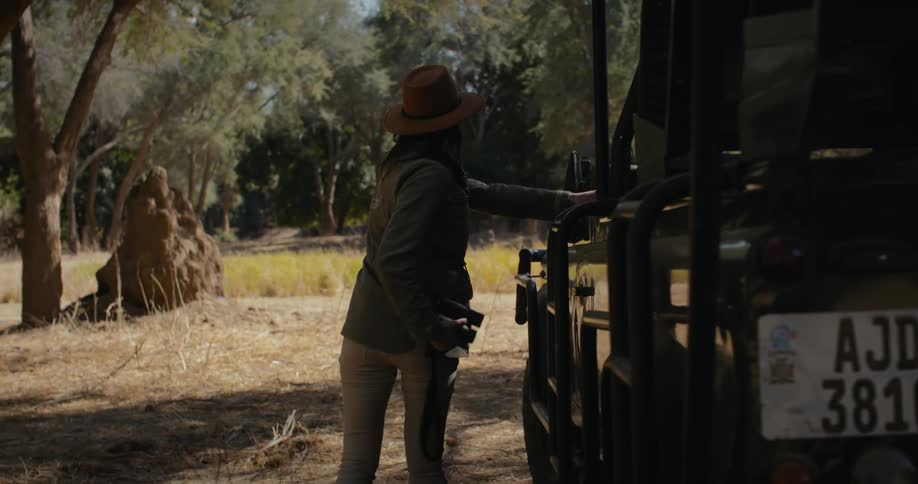 A woman getting out of her car parked in the savanna during the day