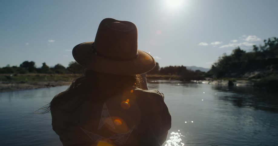 A woman at a lake observing nature during an adventure