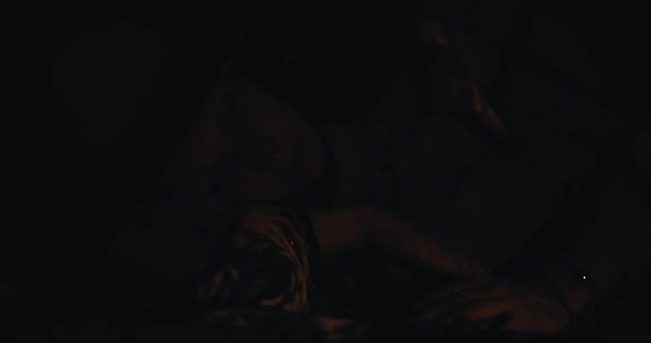 A woman lying down and her face being illuminated by a flash of orange light