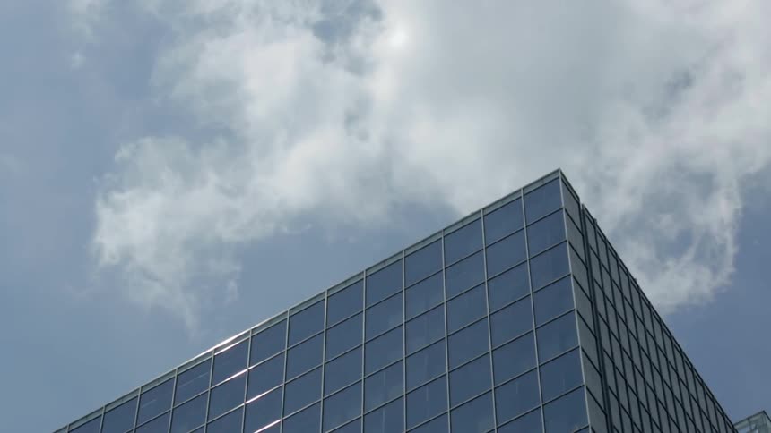 Clouds and bird move past this tall building