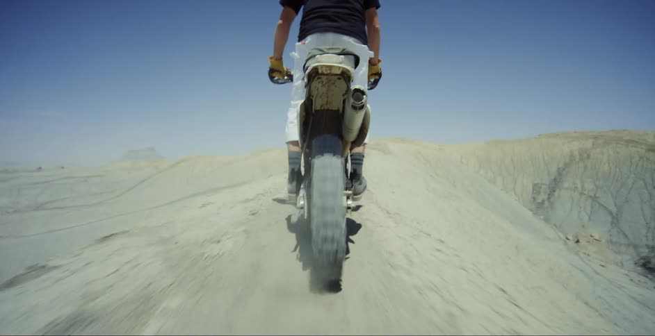 Man riding a motocross bike in the mountains with cliffs on the side