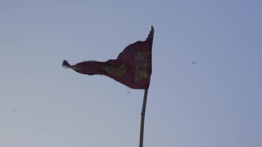 A red flag waving in the wind at sunset