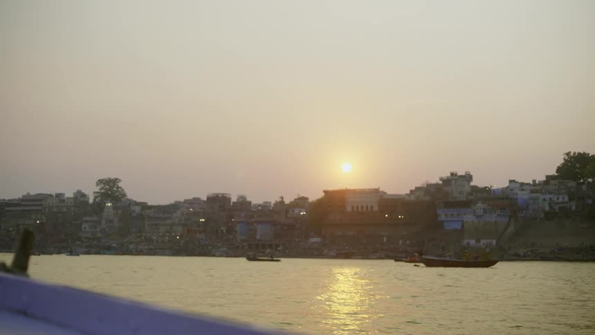 Panorama of the sea with boats and an urban city by the seaside with the sun setting on the horizon