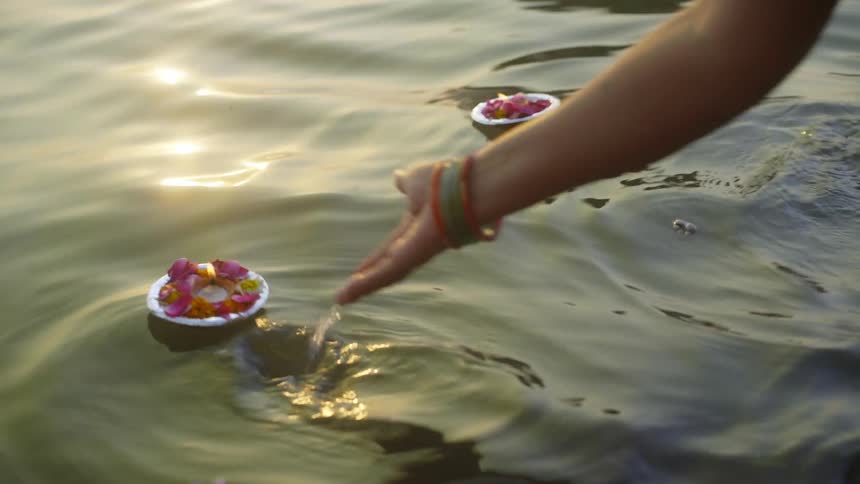 A person placing plate in a river in form of a religion offering
