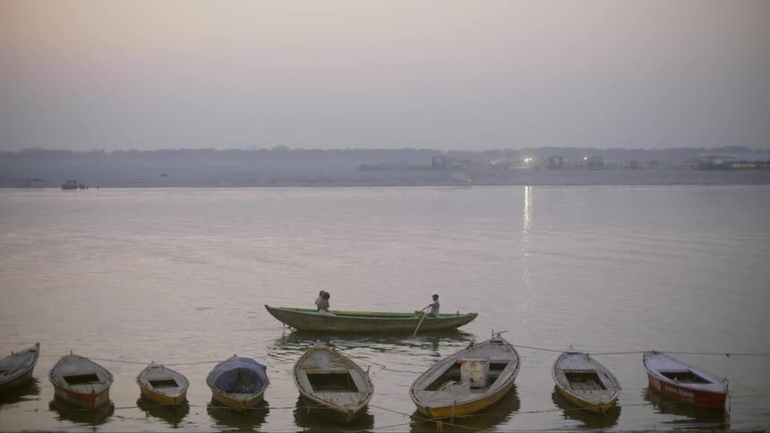 A person moving a canoe with two other person in it