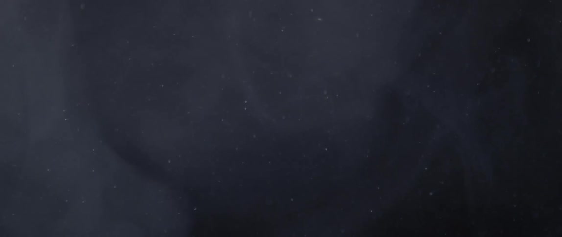 Several white particles falling with a little smoke on a black background