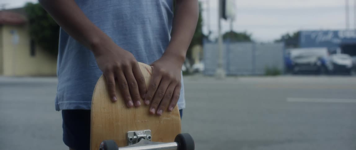 Closeup of a child holding their skateboard with hands