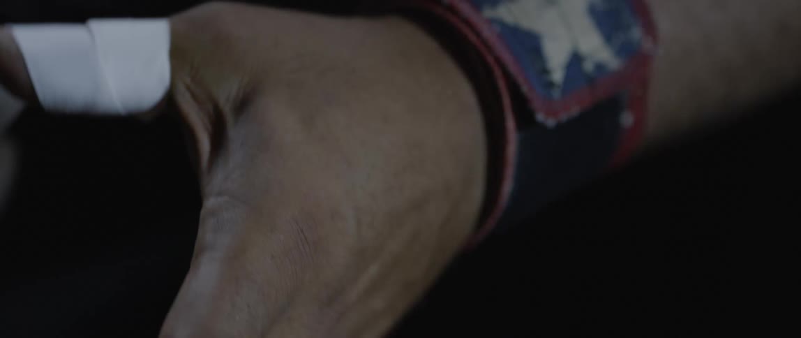 Closeup of a mans hands wrapping his thumb with white tape