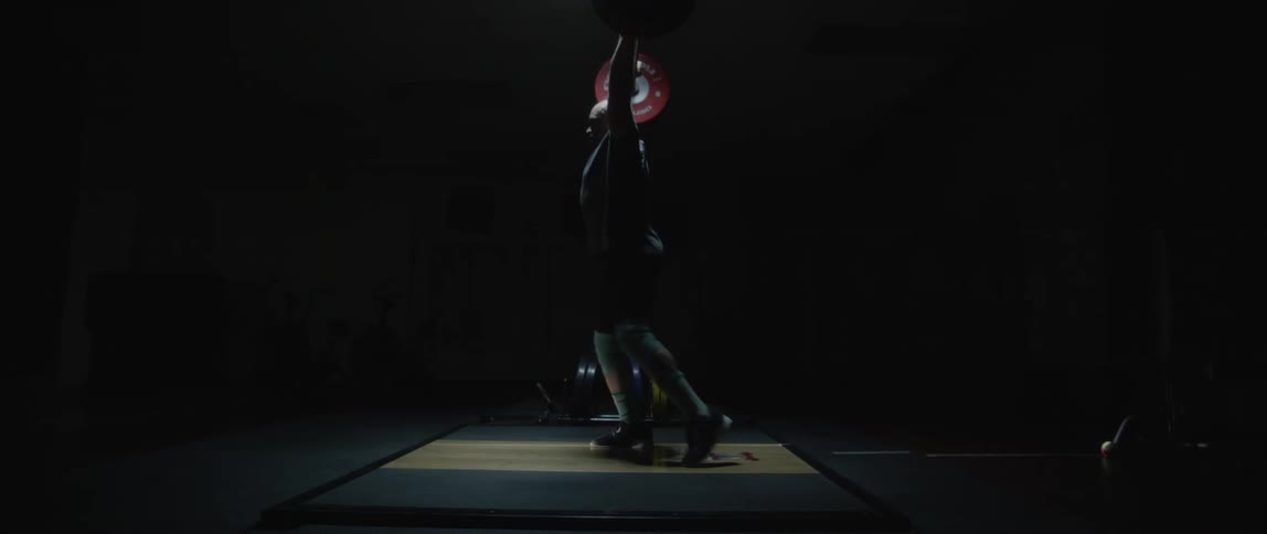A strong man lifting a weight in a gym