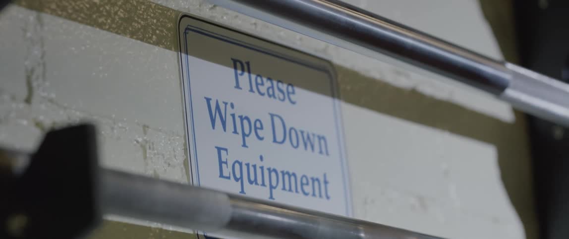 A sign in a workplace that say please wipe down equipment