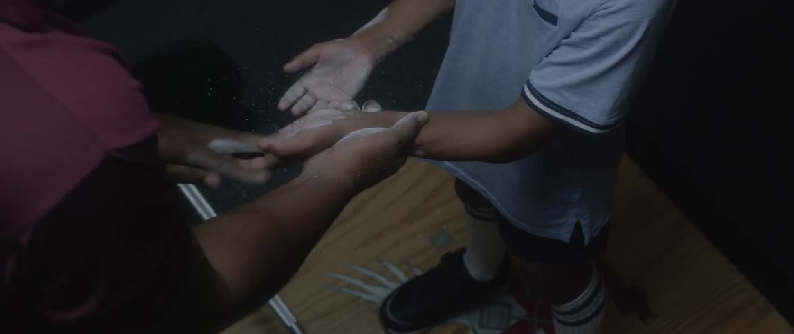Coach coats weightlifting youths hands with chalk dust