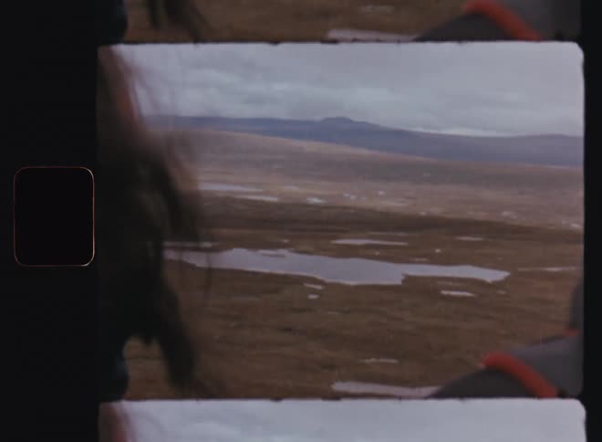 Man and woman with their backs turned observing a landscape with lakes and mountain ranges
