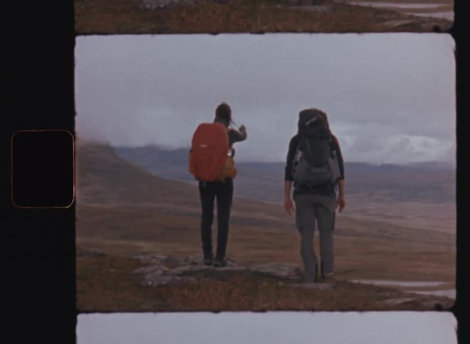 Woman and man with their backs and trail backpacks observing a natural mountain landscape