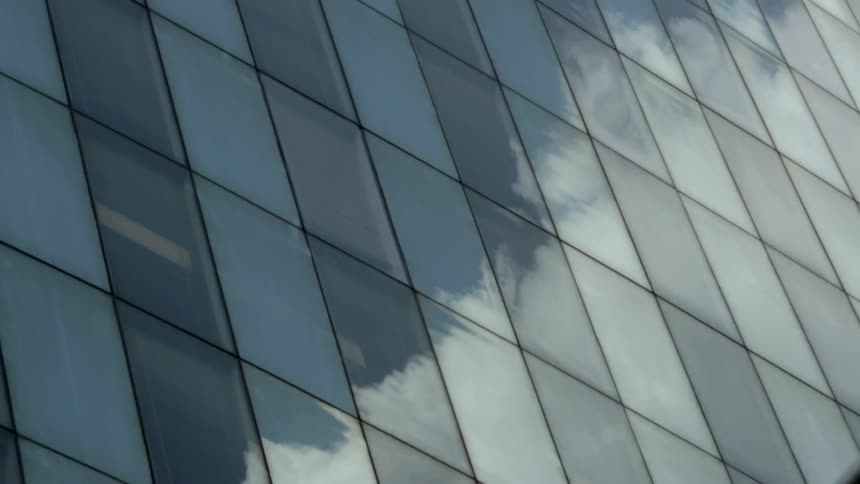 The reflective windows of this building show the passing clouds