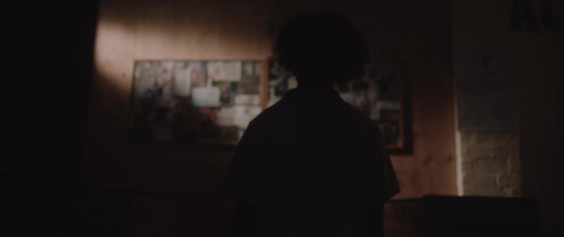 A silhouette of a person looking at photos on a wall