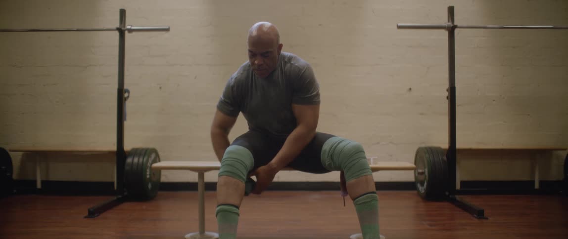 An athlete bandaging his knees sitting on a bench