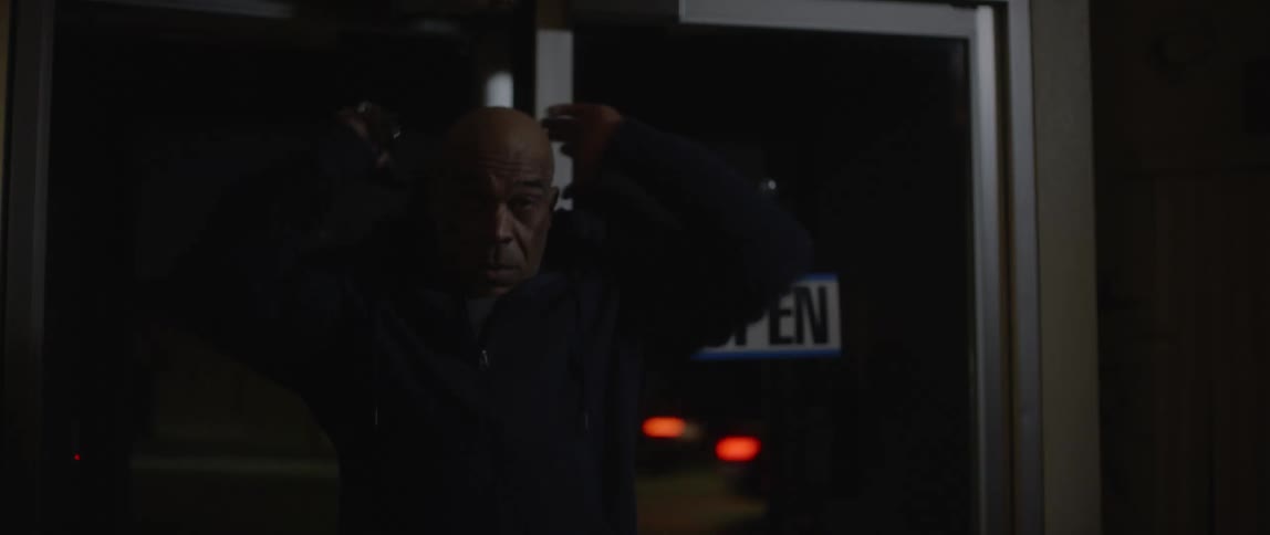 Man walks into a closed establishment located on a busy street and turns on the light before heading to the back