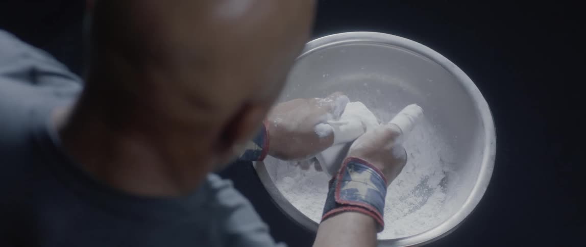 A boxer getting ready to train rub his hands with white powdering substance