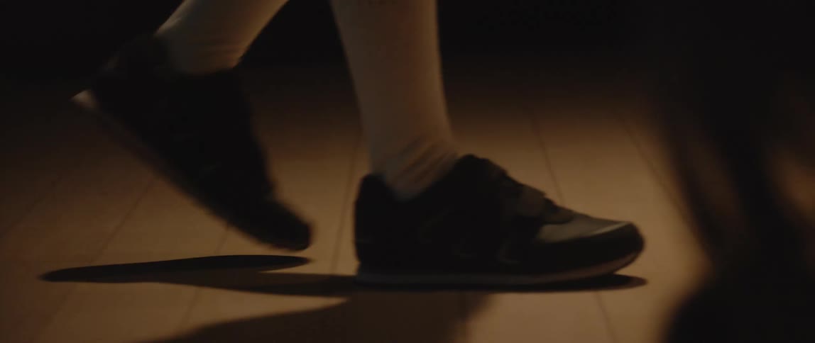 Closeup of a boys feet walking in a dark room