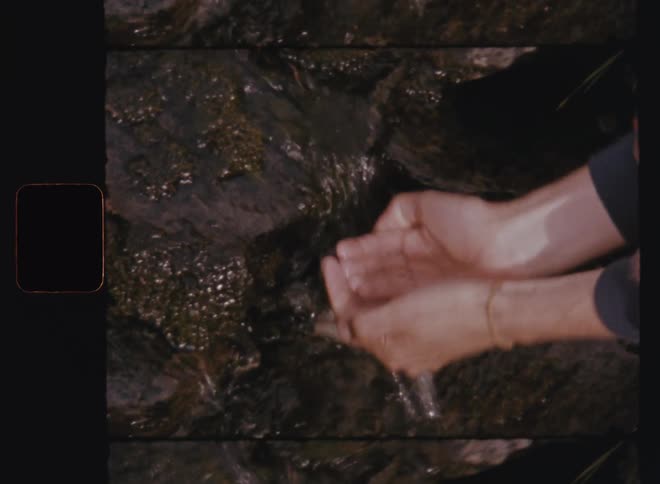A clip of a man drinking from a water flowing on the rock