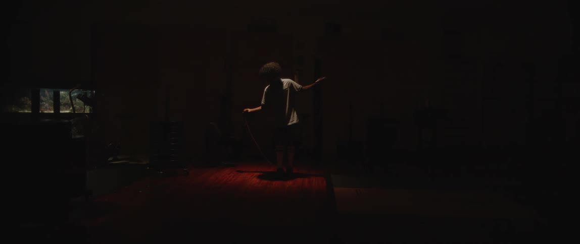 Boy in a darkroom jumping rope for cardio