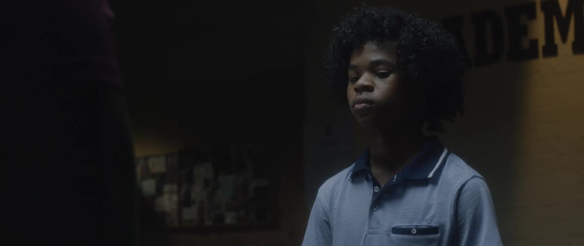 Boy with expression would be concentrated in a dark room and a man next to him crouching