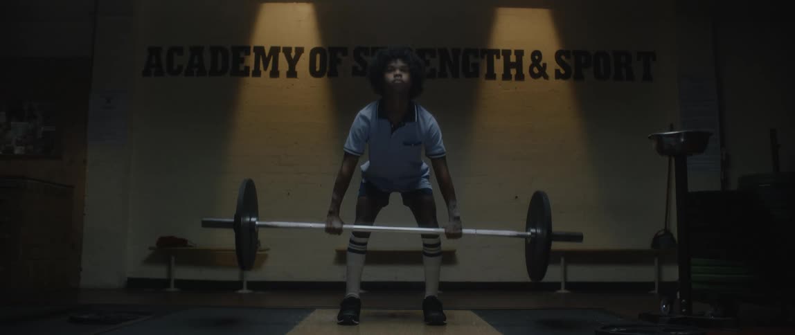 Boy performing a weightlifting with a free barbell