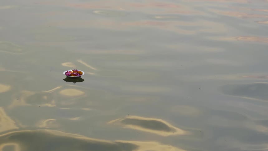 Plate with flowers and a candle amidst the sea