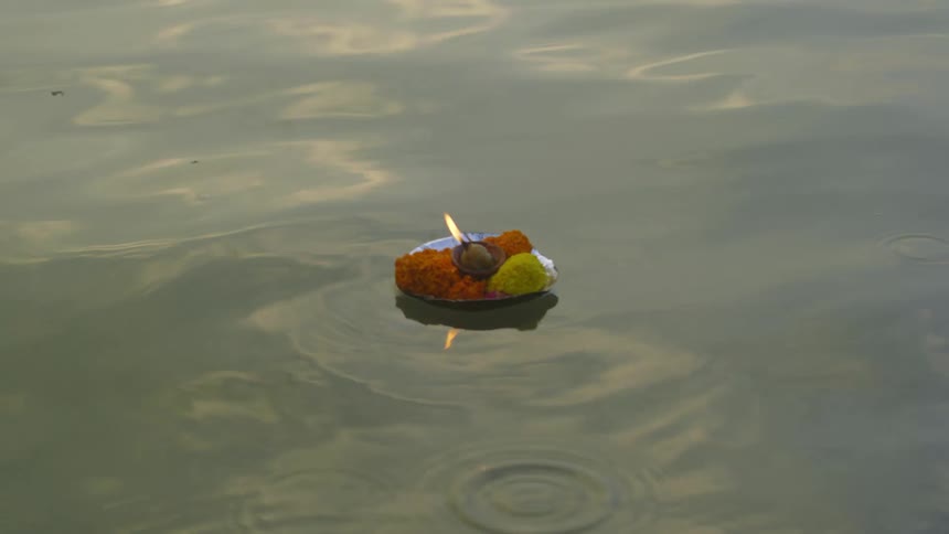 Woman with long hair floats lit lamp in dish on water