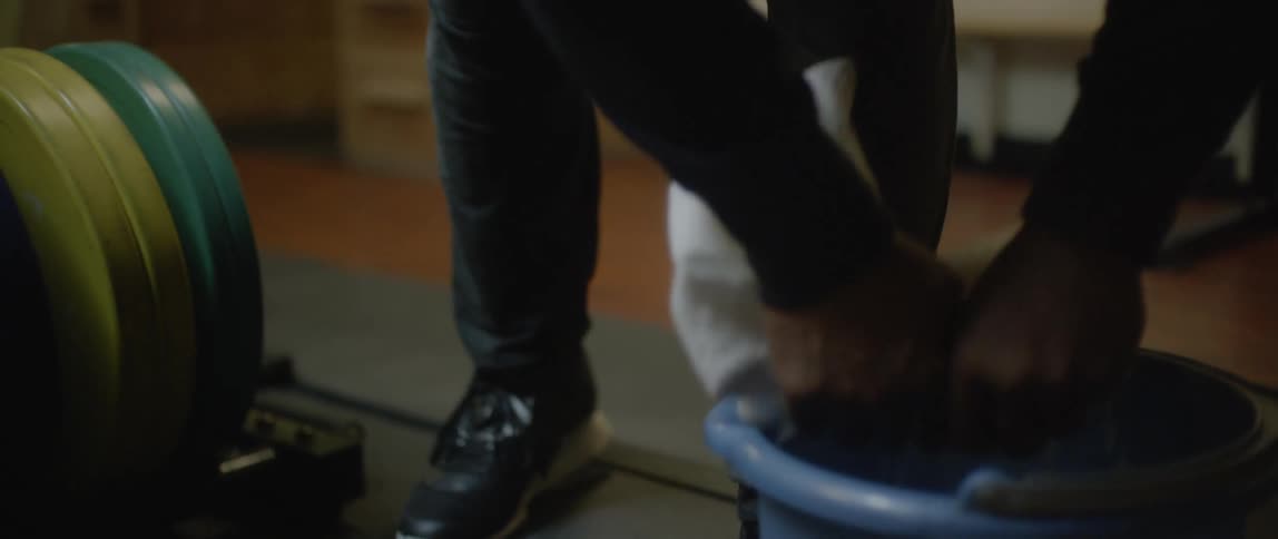 Hands of a man wringing a cloth and removing water over a bucket