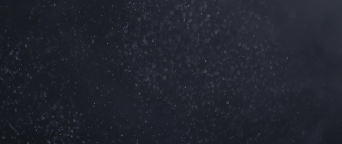 View of a dark sky with white snowflakes falling