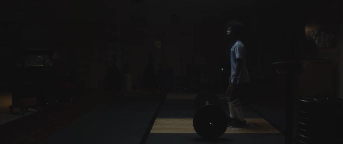 Man crouching standing up and facing a barbell with weights