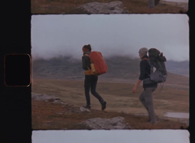 Woman and man walking on a trail through the mountains