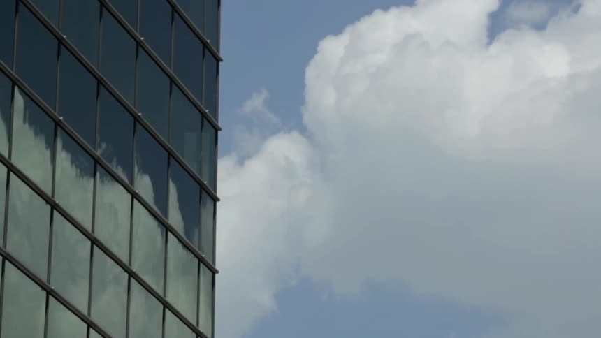 The clouds are moving on the side of this tall building