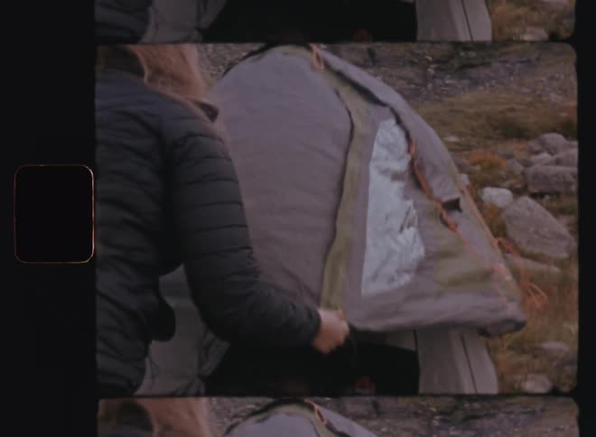 Woman and man setting up a tent amidst the mountains