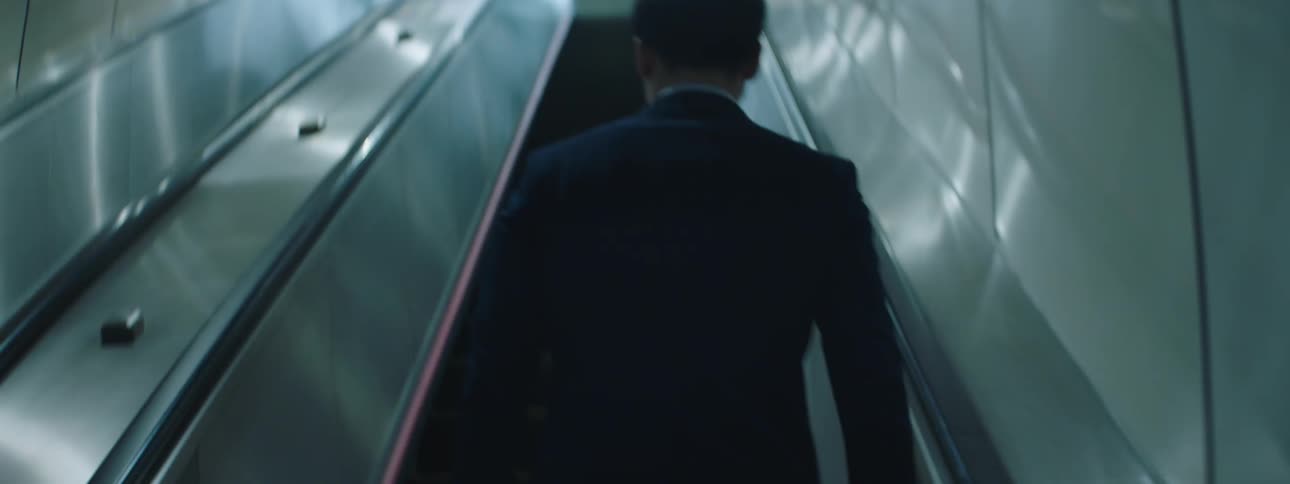 The back of a man in a suit climbing a staircase