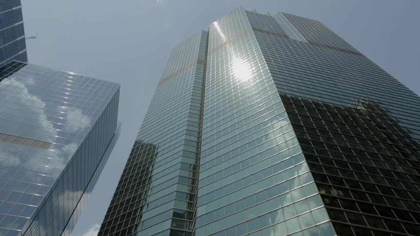 Tall buildings reflect the clouds overhead