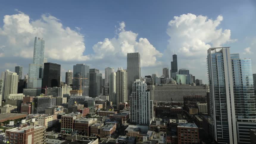 Clouds flow across the sky if a huge city as cars travel along the road