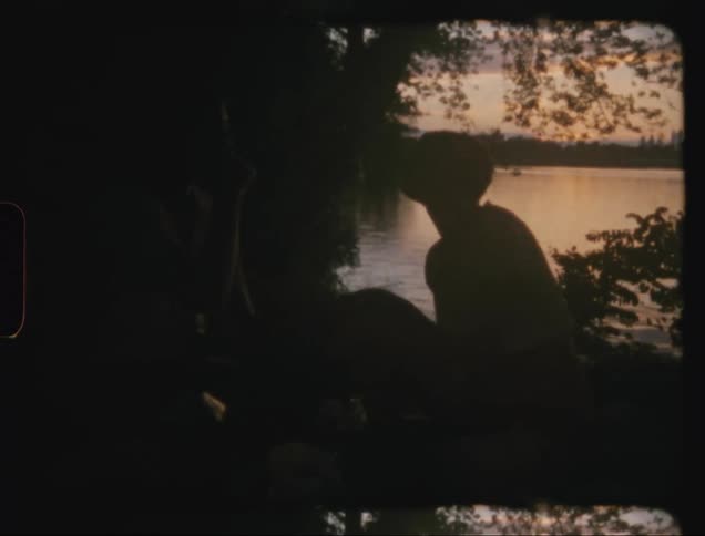 People sitting on the edge of a river during dusk