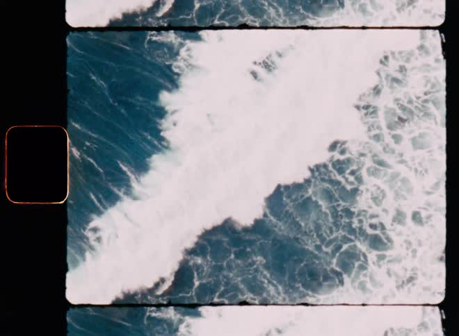A large wave breaks and crashes onto a rocky shoreline